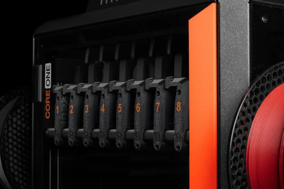 Eight numbered black INDX passive tools parked side by side in their dock inside a Prusa CORE One, each one a thin arm with its own nozzle