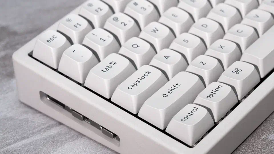 Close-up of the concrete edition&rsquo;s cement-gray keycaps and marble-smooth pale grey shell with a side port cut into the case