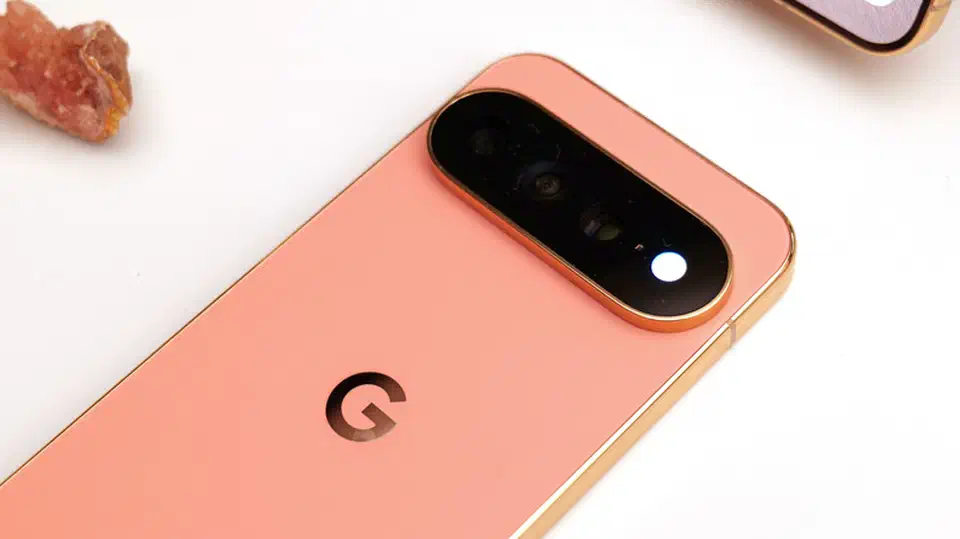 Close-up of a coral Pixel 11 Pro’s rear camera bar with the flash lit bright white where the HiLight LED ring sits